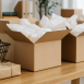 Wide shot of an e-commerce packing desk with shipping boxes and a shopping basket