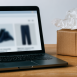 Wide desk shot with a laptop, packed shipping box, and credit card