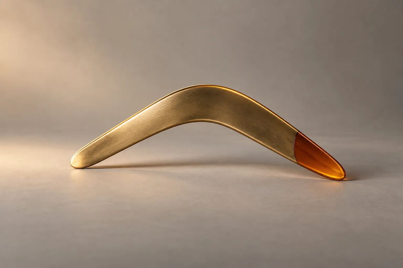 Sculptural brass boomerang with an amber tip representing remarketing ads that bring visitors back
